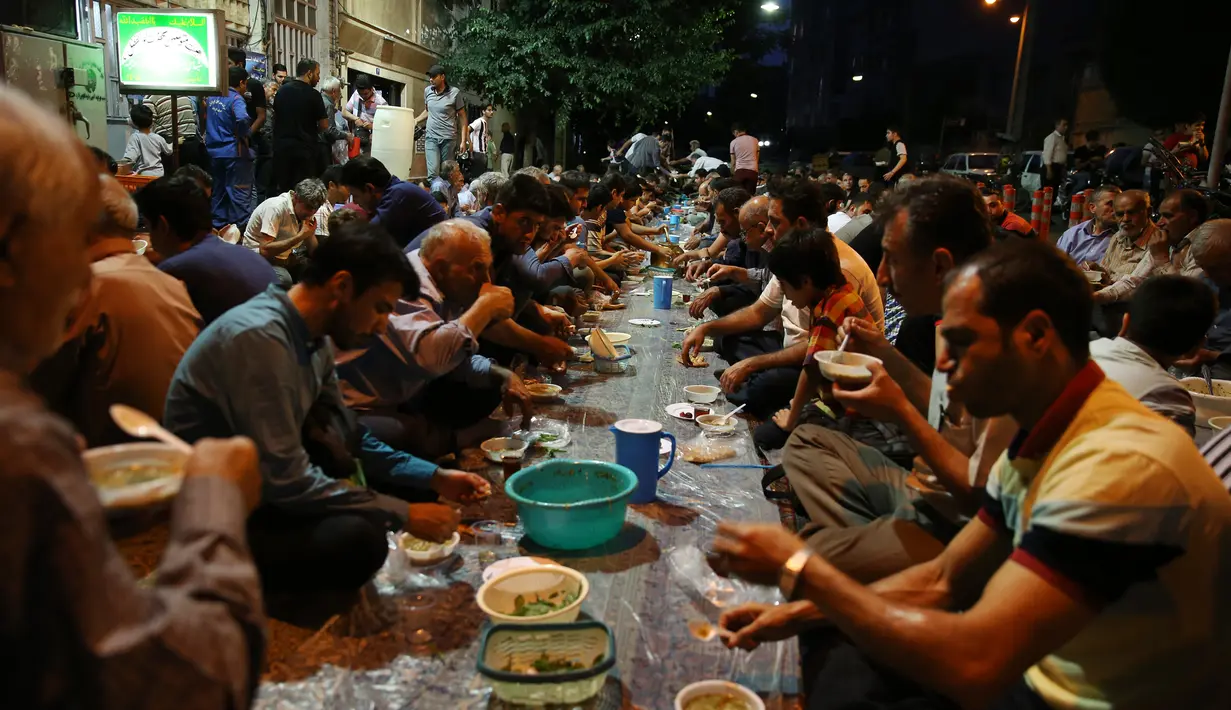 Warga muslim Iran menikmati menu makanan berbuka puasa di sebuah jalan di Teheran, 29 Mei 2018. Sebagian besar warga muslim Iran melaksanakan ibadah puasa di bulan Ramadan sesuai ajaran Islam melalui Nabi Muhammad. (AP Photo/Vahid Salemi)