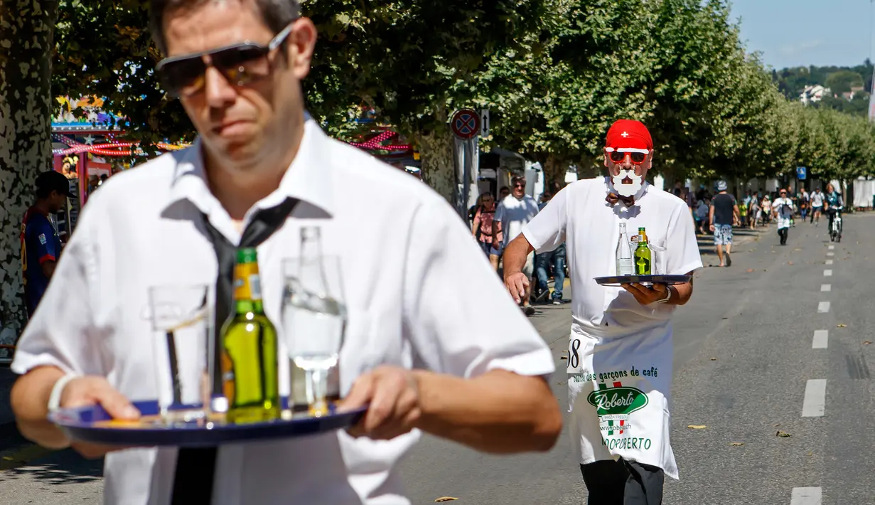 Pramusaji beradu kecepatan sambil membawa nampan dalam Waiters Race ke-21 di Fetes de Geneve, Swiss, 6 Agustus 2017. Lomba yang tak biasa ini diikuti oleh 80 peserta yang merupakan pelayan restoran dan kafe. (Salvatore Di Nolfi/Keystone via AP)