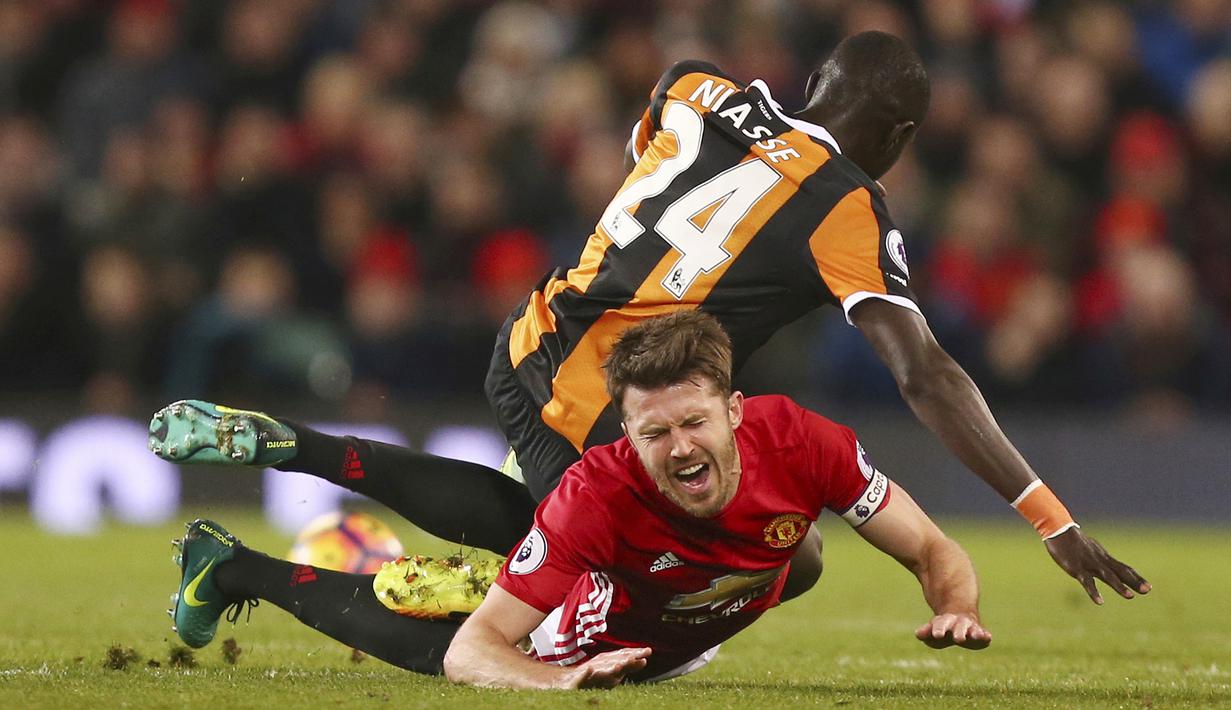 Pemain Hull City, Oumar Niasse menjatuhkan Michael Carrick saat perebutan bola pada lanjutan Premier League pekan ke-23 di Old Trafford, Manchester, selasa (01/02/2017) waktu setempat. MU bermain imbang 0-0. (AP/Dave Thompson)