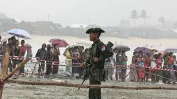 Seorang tentara berjaga saat proses evakuasi jasad korban kecelakaan pesawat militer yang jatuh ke laut Andaman, di pantai Launglon, Myanmar, Kamis (8/6). Ratusan orang berkumpul di pinggir pantai untuk menyambut jenazah. (AP Photo/Esther Htusan)