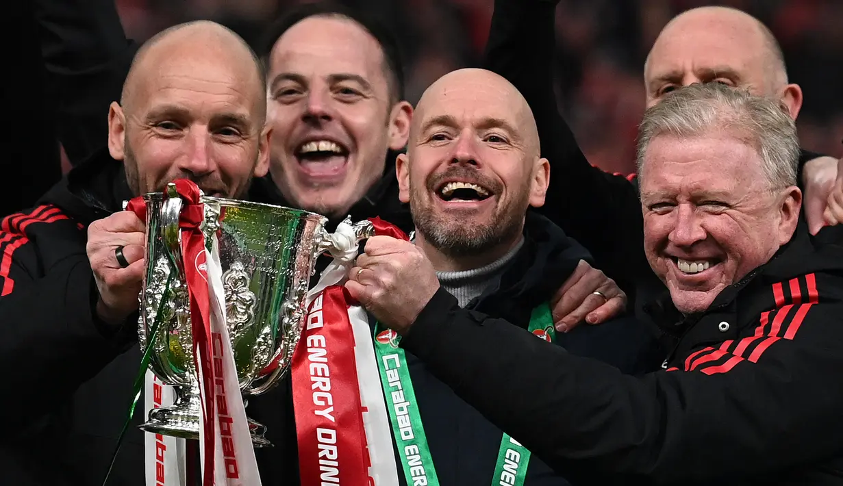 <p>Pelatih Manchester United, Erik Ten Hag bersama sejumlah asisten pelatih memamerkan trofi Carabao Cup 2023 setelah mengalahkan Newcastle United di Wembley Stadium, Minggu (26/2/2023) waktu setempat. Ini merupakan trofi pertama yang dipersembahkan pelatih asal Belanda tersebut. (AFP/Glyn Kirk)</p>