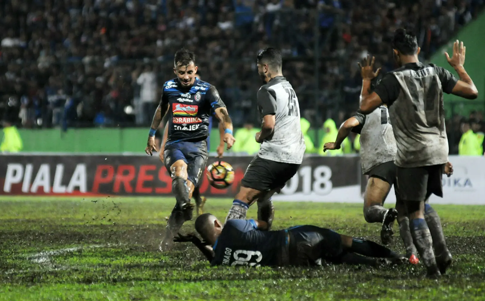 Pemain Arema jatuh bangun saat menghadapi Persela karena lapangan di Stadion Gajayana, Malang, licin. (Bola.com/Iwan Setiawan)