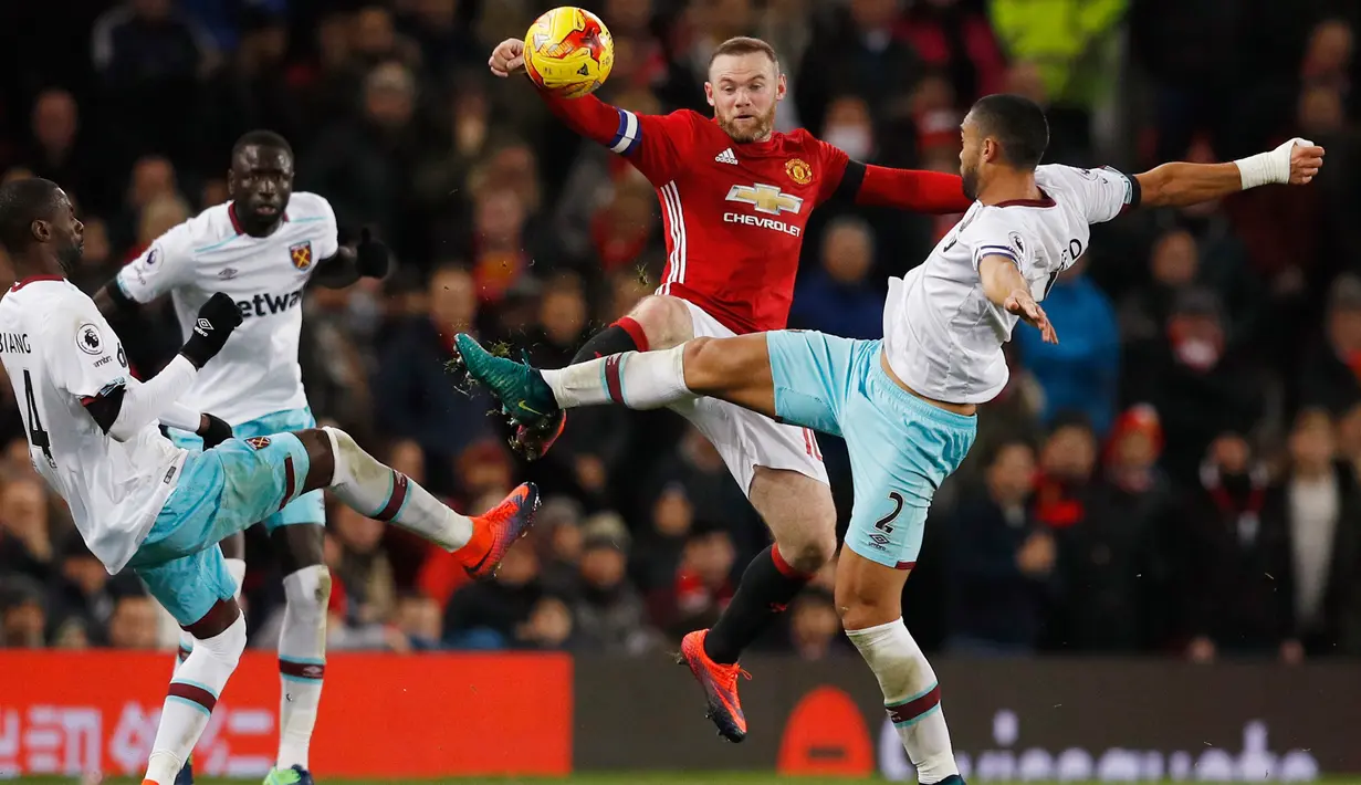 Penyerang MU, Wayne Rooney berebut bola dengan tiga pemain West Ham United di perempat final Piala Liga (EFL Cup) di Stadion Old Trafford, Inggris, (1/12). MU menang telak atas West Ham dengan skor 4-1. (Reuters/Phil Noble)