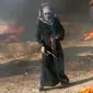 Pengunjuk rasa wanita Palestina memegang ketapel di tengah asap hitam saat terjadi bentrok antara warga dengan tentara Israel di Khan Younis, perbatasan Gaza, Jumat (10/8). (AP Photo/Adel Hana)