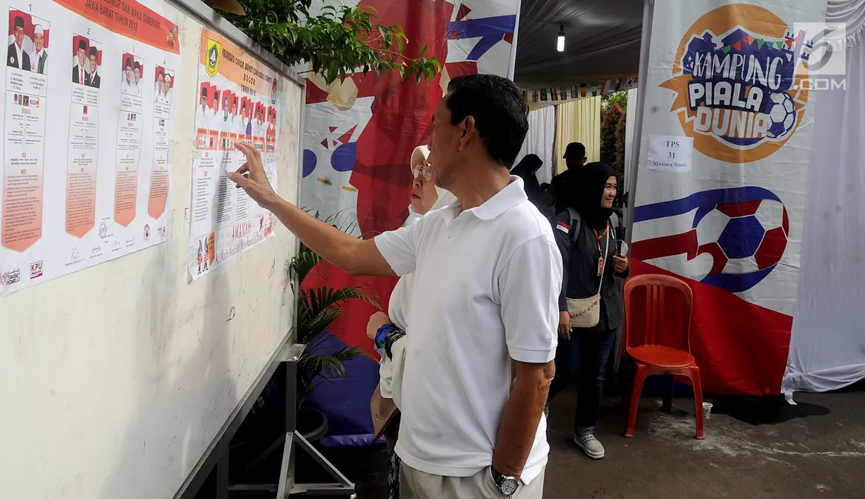 Warga melihat foto Cagub dan Cawagub Jawa Barat pada Pilkada Serentak 2018 di TPS 31 Mutiara Sentul, Bogor, Rabu (27/6). TPS ini didekorasi dengan konsep piala dunia untuk menarik minat pemilih agar hadir dalam pencoblosan. (Merdeka.com/Arie Basuki)