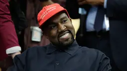 Rapper Kanye West saat bertemu dengan Presiden AS, Donald Trump di Oval Office, Gedung Putih, Kamis (11/10). West mengenakan topi bertuliskan slogan yang kerap digaungkan Trump, yakni "Make America Great Again". (AP/Evan Vucci)