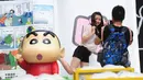 Seorang wanita (tengah) berpose saat pameran Crayon Shin-chan di Shenyang, China, 11 Juli 2015. Pameran ini menandai ulang tahun ke 25 dari seri manga Jepang, Crayon Shin-chan. (CHINA OUT AFP PHOTO) 