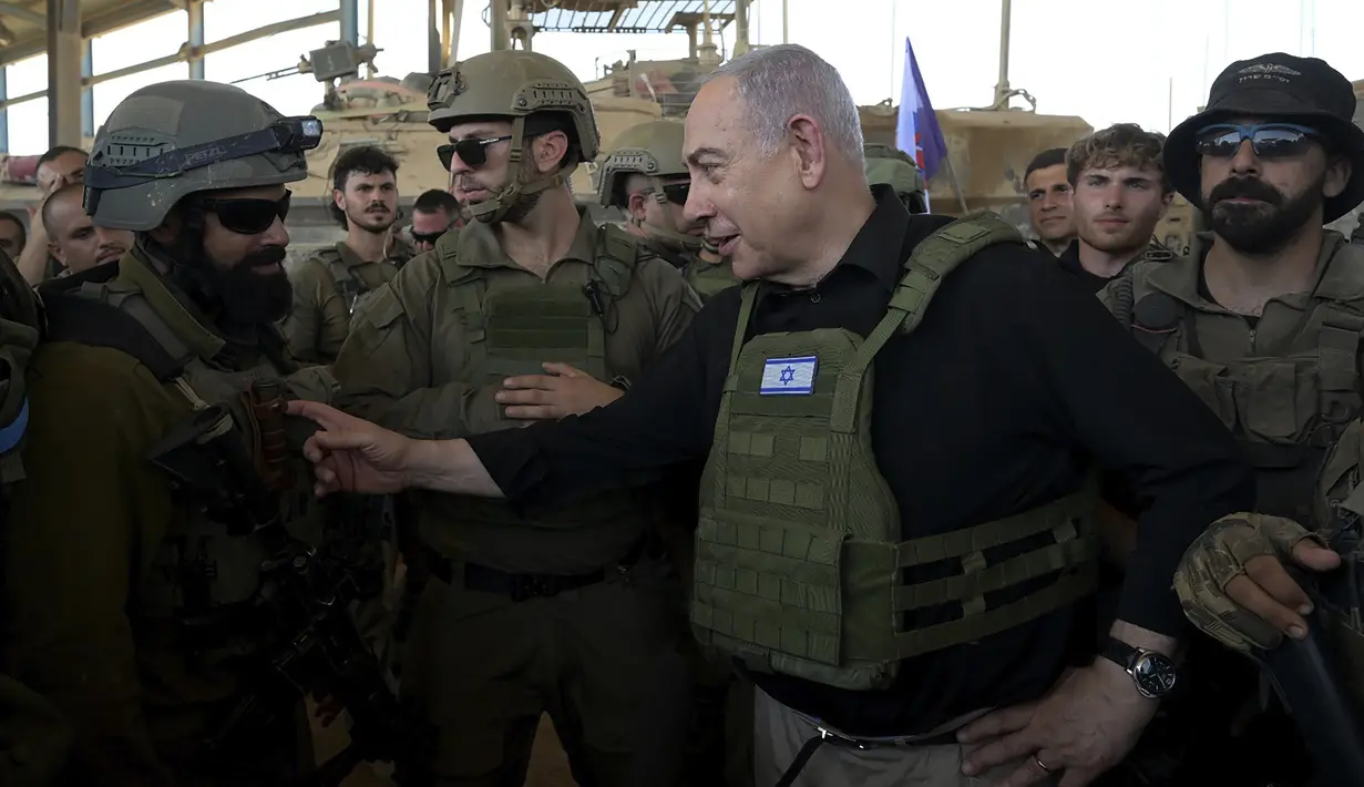 Netanyahu terlihat mengenakan rompi anti peluru berwarna hijau dikelilingi prajurit IDF. (Avi Ohayon/Israel Prime Minister's Office via AP)