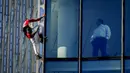 Alain Robert yang dikenal sebagai 'Spiderman Prancis' (kiri) memanjat gedung pencakar langit Skyper di pusat Frankfurt, Jerman, 23 November 2021. Alain Robert memanjat gedung setinggi 153 meter itu untuk meningkatkan kesadaran dunia tentang masalah perubahan iklim. (AP Photo/Michael Probst)