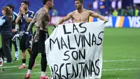 Gelandang Argentina Giovani Lo Celso menunjukkan spanduk bernuansa politik usai semifinal Piala Dunia 2026 melawan Inggris. (AFP/Thomas Coex)