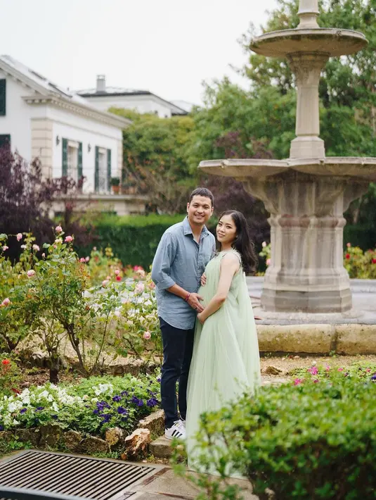 Potret maternity shoot lainnya yang tak kalah memesona. Jessica Tanoesoedibjo dan sang suami berpose mesra. Jessica mengenakan gaun hijau off-the-shoulder yang flowy menjuntai ke lantai.