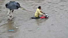 Seorang pengendara sepeda motor mendorong sepedanya melalui jalan yang banjir setelah hujan lebat di Lahore pada 5 Juli 2023. (AFP/Arif Ali)
