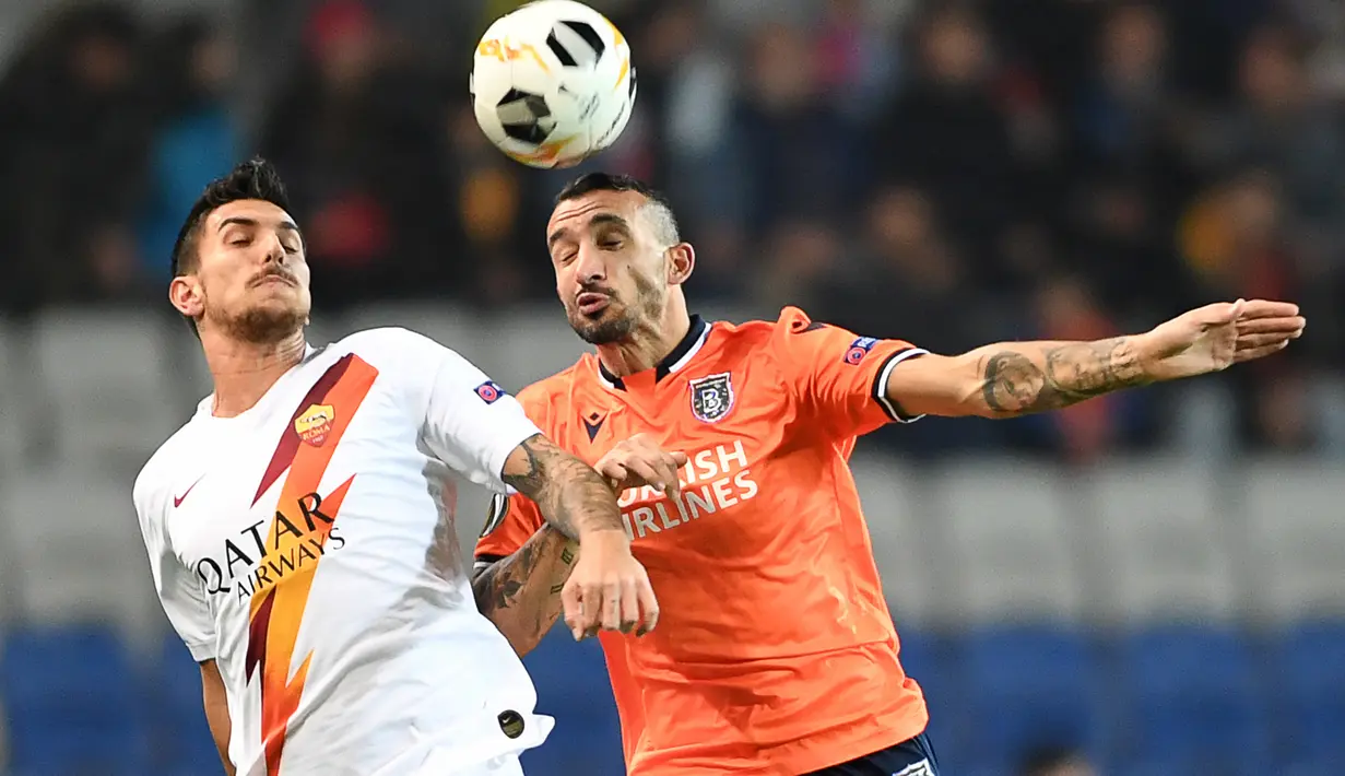 Bek Istanbul Basaksehir, Mehmet Topal menyundul bola saat berebut dengan gelandang AS Roma, Lorenzo Pellegrini pada laga kelima Grup J Liga Europa 2019-2020 di stadion Fatih Terim, Kamis (28/11/2019). AS Roma menang meyakinkan dengan skor 3-0.  (Ozan KOSE / AFP)