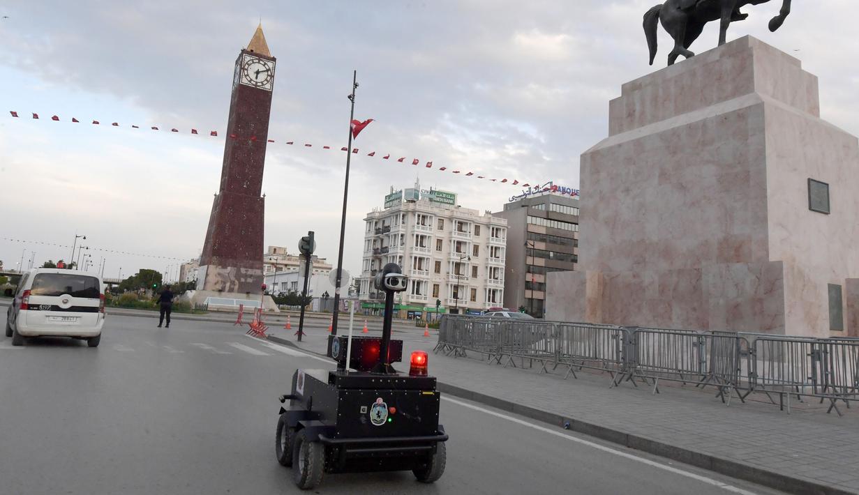 Sebuah robot polisi Tunisia berpatroli selama kebijakan penguncian (lockdown) di sepanjang Avenue Habib Bourguiba, pusat ibu kota Tunis, Rabu (1/4/2020). Robot ini dilengkapi dengan deteksi termal (temperatur tubuh manusia) dan kemampuan video audio secara real time. (FETHI BELAID/AFP)