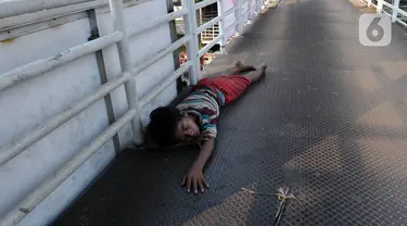 Seorang anak tertidur di Jembatan Penyebrangan Orang (JPO) kawasan Glodok, Jakarta Sabtu (22/7/2023). Berdasarkan data penyandang masalah kesejahteraan sosial anak jalanan yang dipublikasikan oleh Kementerian Sosial pada tahun 2012, jumlah anak jalanan di Indonesia mencapai angka 135.598 ribu jiwa. (merdeka.com/Imam Buhori)