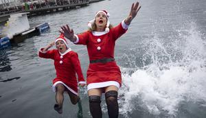 Sejumlah peserta berkostum Sinterklas melompat ke dalam air dalam ajang Copa Nadal yang berlangsung di Barcelona's Port Vell, Barcelona, Kamis (25/12/2025) waktu setempat. Acara tersebut diikuti lebih dari 450 peserta. (AFP/Josep Lago)