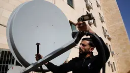 Pegawai Trans Media memeriksa sebuah satelit di kantornya setelah penutupan oleh pasukan Israel di kota Hebron, Tepi Barat, Rabu (18/10). Dalam penggerebekan, delapan perusahaan media diperintahkan untuk berhenti beroperasi. (HAZEM BADER/AFP)