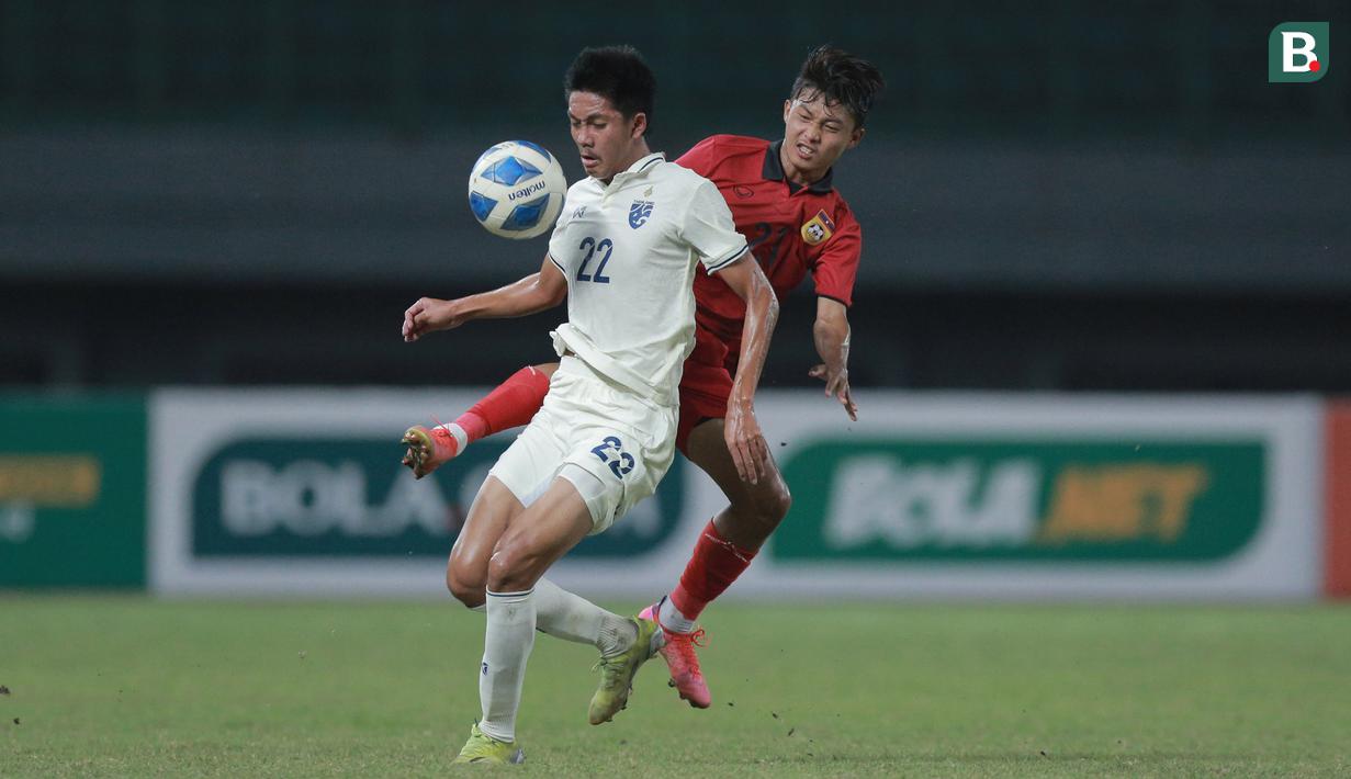 <p>Pemain Timnas Thailand U-19, Phanthamit Praphanth (kiri) berebut bola dengan pemain Timnas Laos U-19, Vongsadka Chanthaleuxay&nbsp;saat laga semifinal Piala AFF U-19 2022 yang berlangsung di Stadion Patriot Candrabhaga, Bekasi, Rabu (13/07/2022). (Bola.com/M Iqbal Ichsan)</p>