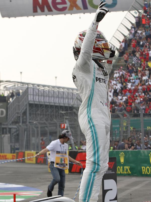 Pembalap Mercedes dari Inggris, Lewis Hamilton berdiri di atas mobilnya setelah menjuarai balapan GP Meksiko di Autodromo Hermanos Rodriguez, Mexico City (28/10/2019). (AP Photo/Rebecca Blackwell)