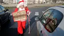 Remi Le Calvez, menghampiri sebuah mobil saat ia mencari tumpangan dengan mengenakan kostum Santa Claus di Paris, Prancis, Selasa (6/12). Remi membagi pengalaman dari perjalanannya kepada orang-orang lewat blog dan Facebooknya. (Reuters/Benoit Tessier)