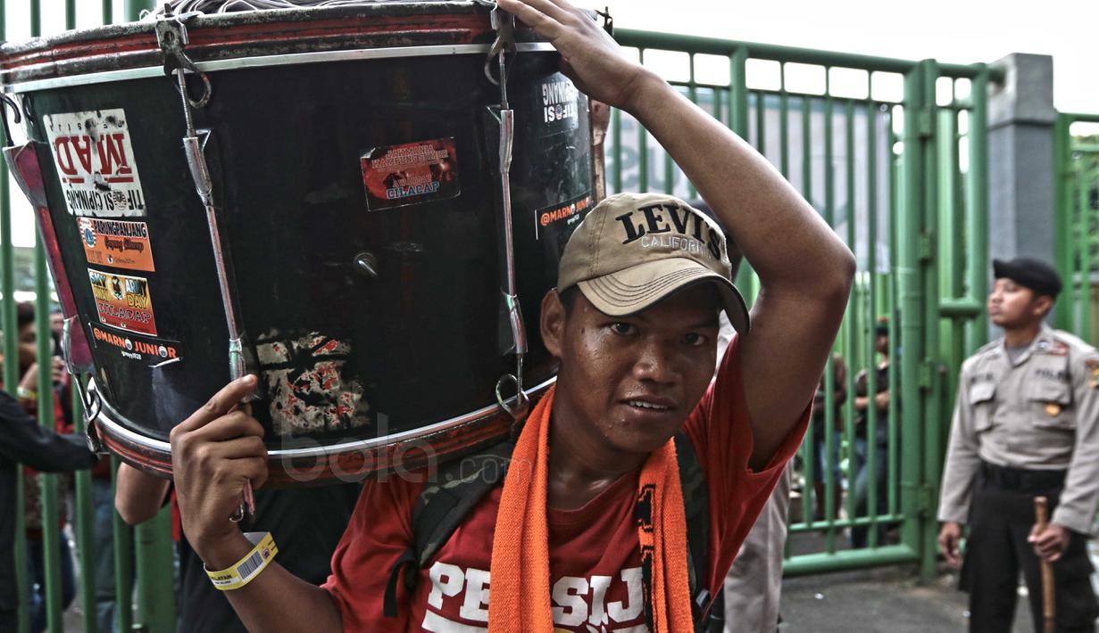 Seorang The Jakmania memikul gendang kedalam stadion untuk mengiringi nyanyian rekan-rekannya di Stadion Patriot, Bekasi, Kamis (4/5/2017). The Jakmania hadir untuk mendukung Persija Jakarta melawan Madura United. (Bola.com/Nicklas Hanoatubun)