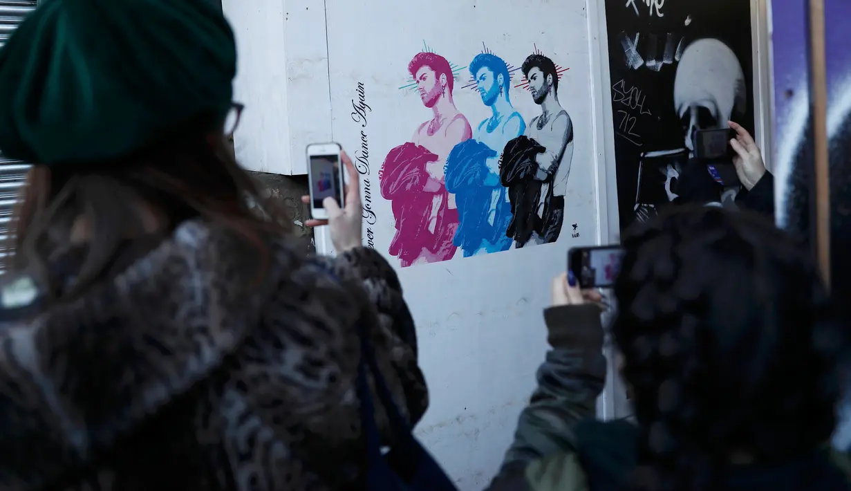 Dua orang wanita mengambil gambar mural musisi asal Inggris, George Michael, di Shoreditch, London timur, 29 Desember 2016. Mural itu diciptakan seorang seniman jalanan Pegasus sebagai penghormatan terhadap mendiang George Michael (REUTERS/Stefan Wermuth)