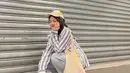 Kombinasi striped shirt dengan celana jeans, hijab, dan topi baseball nyaman dan stylish untuk hangout. [Foto: IG/putridelinaa].