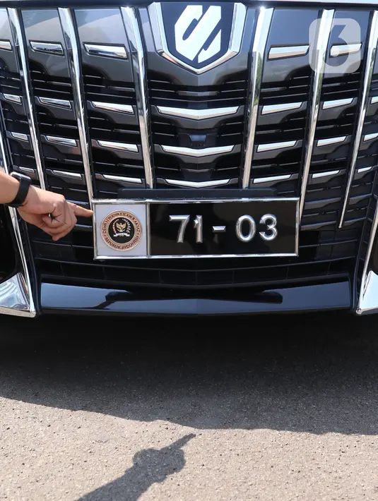 Seorang petugas menunjukan logo pada kendaraan dengan plat nomor khusus anggota DPR yang terparkir di Kompleks Parlemen, Senayan, Jakarta, Selasa (25/5/2021).  Penggunaan plat nomor khusus tersebut hanya menyempurnakan penggunaan atribut logo DPR. (Liputan6.com/Angga Yuniar)