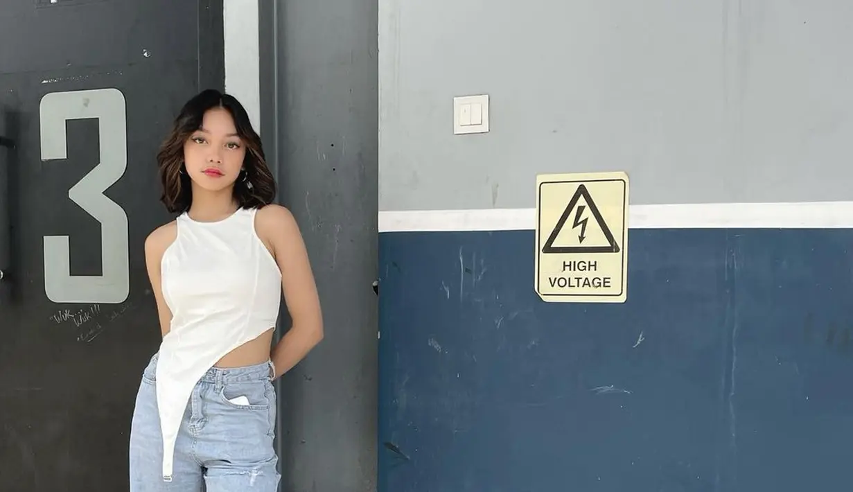 Outfit Naura Ayu yang satu ini memiliki look yang boyish namun tetap stylish. Ia mengenakan halter top dengan asymetric cut di bagian bawah, yang kemudian dipadukan dengan ripped jeans dan sneakers. Meski tampil boyish, kesan feminin bisa diaplikasikan pada makeup. (instagram/naura.ayu)