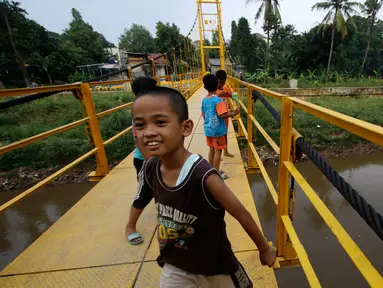 Ekspresi anak-anak saat bermain di sekitar jembatan gantung di kawasan Tanjung Barat, Jakarta Selatan, Senin (22/5). Sejumlah warga mengeluhkan desain konstruksi jembatan yang kerap menjadi tempat bermain anak. (Liputan6.com/Immanuel Antonius)