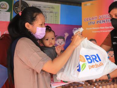 Warga menerima bantuan paket sembako dari BRI di Posyandu Batu Jaya, Batu Ceper, Kota Tangerang, Rabu (25/01/2022). Bantuan yang diberikan sebagai Tanggung Jawab Sosial Lingkungan (TJSL)/CSR BRI Peduli Stunting digelar dalam rangka Hari Gizi Nasional. (Liputan6.com/HO/Humas BRI)