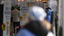 Petugas kesehatan yang mengenakan alat pelindung diri berdiri untuk membantu pengunjung di klinik skrining sementara untuk virus corona dekat Balai Kota Seoul, Seoul, Korea Selatan, Rabu (26/1/2022). (AP Photo/Lee Jin-man)