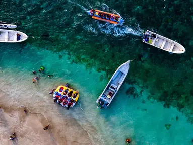 Pemandangan udara menunjukkan orang-orang saat berkumpul menikmati masa libur panjang Idulfitri di area olahraga air, Pantai Lhoknga, Aceh, pada Kamis 26 Maret 2026. Libur perayaan Idulfitri 1447 Hijriah memberi kesempatan panjang bagi warga Aceh untuk berwisata, salah satunya ke Pantai Lhoknga. (Chaideer MAHYUDDIN/AFP)