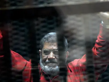 Mantan Presiden Mesir Mohammed Morsi mengenakan seragam merah yang menandakan dia telah dijatuhi hukuman mati saat menjalani sidang sementara di Akademi Kepolisian Nasional, Kairo, Mesir, 21 Juni 2015. Mohammed Morsi meninggal pada Senin 17 Juni 2019 waktu setempat. (AP Photo/Ahmed Omar, File)