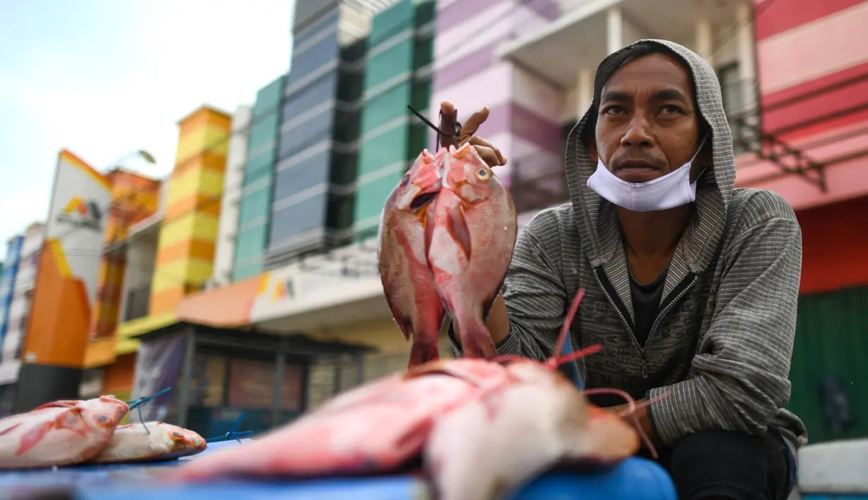 Penjual menunjukkan ikan dagangannya di sebuah pasar tradisional usai gempa dan tsunami melanda Palu, Sulawesi Tengah, Kamis (4/10). Banyak warga berdatangan untuk berbelanja saat pasar mulai buka. (Permata SAMAD/AFP)
