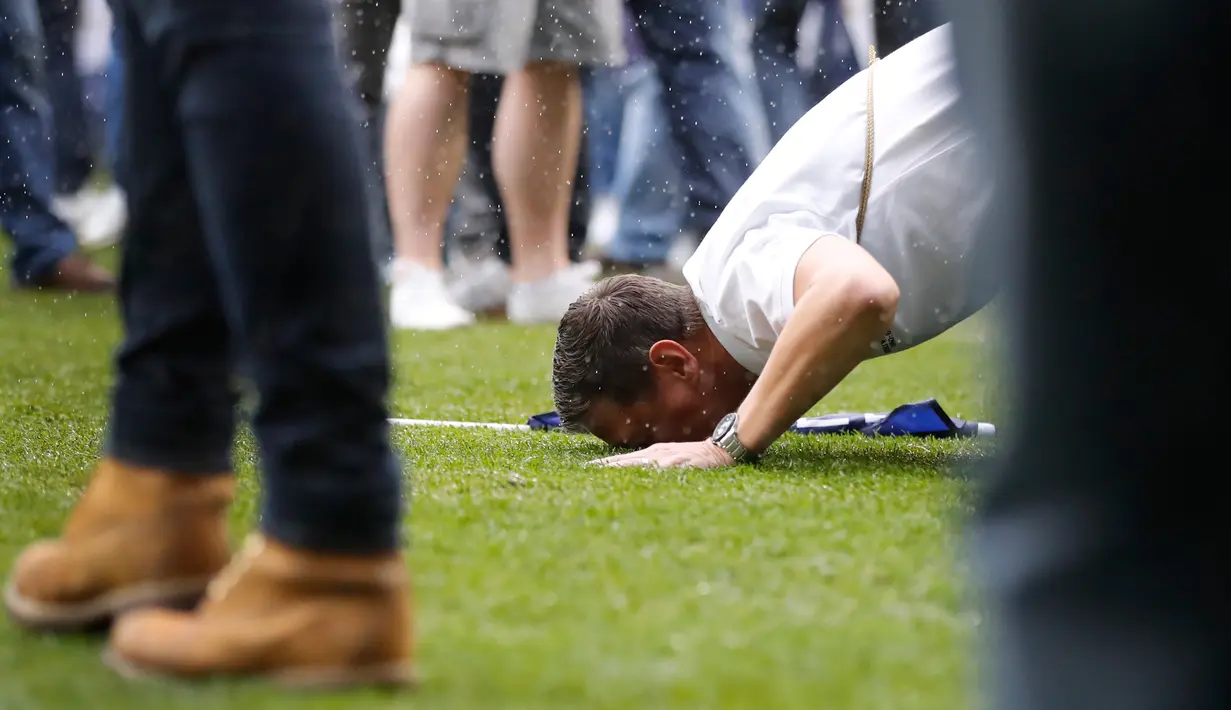 Seorang supporter Tottenham Hotspur mencium rumput lapangan usai pertandigan di Liga Inggris di stadion White Hart Lane, London, (14/5). Biaya pembangunan stadion tersebut mencapai sekitar Rp 13 triliun rupiah. (AP/Frank Augstein)
