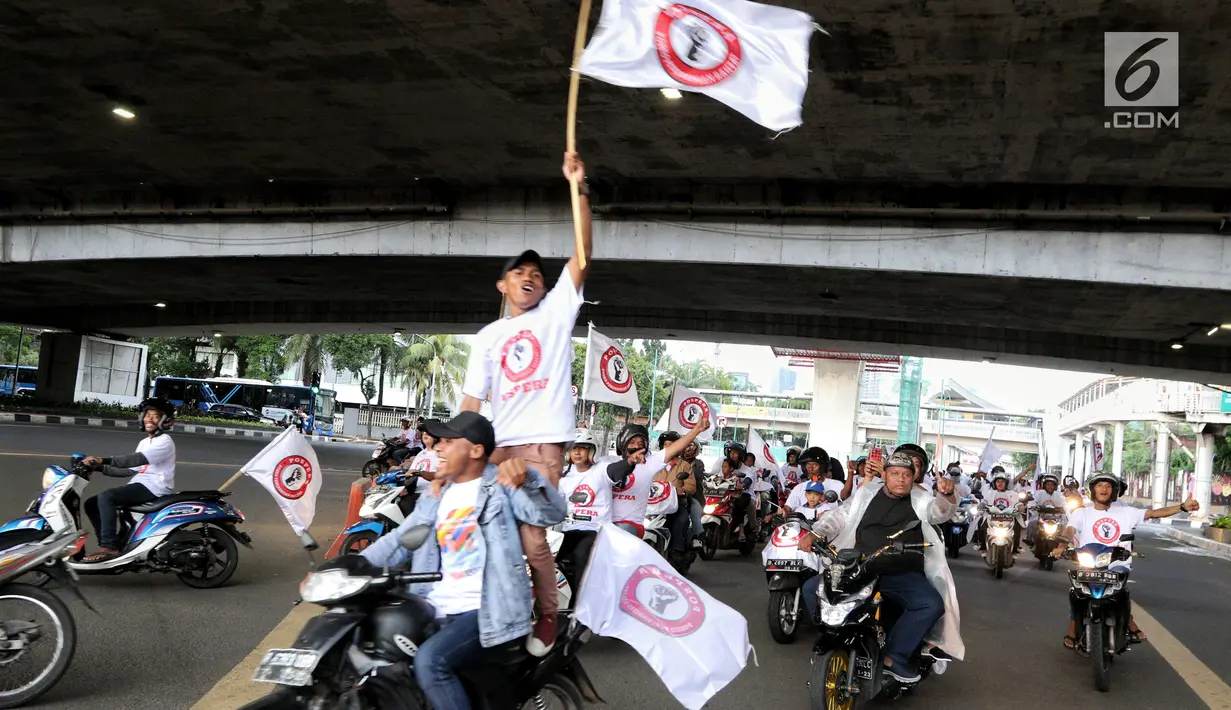 Relawan capres dan cawapres nomor urut 01 Joko Widodo atau Jokowi dan Ma'ruf Amin mengibarkan bendera saat konvoi menuju lokasi debat Pilpres 2019 di Jakarta, Minggu (17/2). Massa konvoi menggunakan sepeda motor, bus, dan truk. (Liputan6.com/JohanTallo)