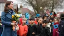 The Duchess of Cambridge, Kate Middleton berjalan sambil membawa bunga saat tiba di Roe Green Junior School di London, Selasa, (23/1). Kunjungan ini sekaligus peluncuran program kesehatan mental untuk anak-anak. (AP Photo/Frank Augstein)