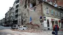 Gempa Terparah dalam 140 Tahun di Kroasia: Warga melewati bangunan yang rusak dan mobil-mobil hancur oleh puing-puing setelah gempa di jalan-jalan pusat kota Zagreb (22/3/2020).  Gempa magnitudo 5,3 ini tercatat sebagai yang terbesar, yang mempengaruhi Kroasia dalam 140 tahun. (AFP/Damir Sencar)