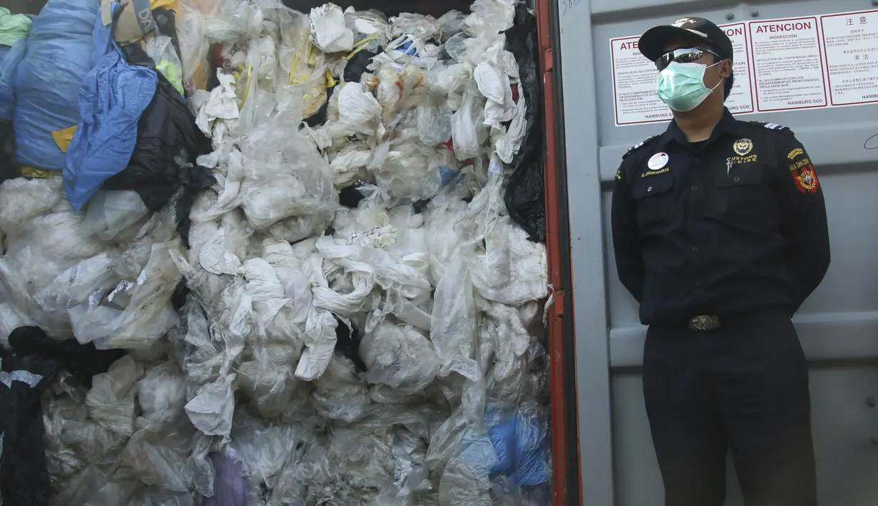 Petugas berjaga dekat peti kemas berisi sampah plastik yang mengandung limbah berbahaya dan beracun (B3) untuk di re-ekspor di Batam, Senin (29/7/2019). Indonesia mengirim kembali (re-ekspor) tujuh peti kemas berisi limbah plastik impor ke negara asalnya, Prancis dan Hongkong. (SEI RATIFA/AFP)