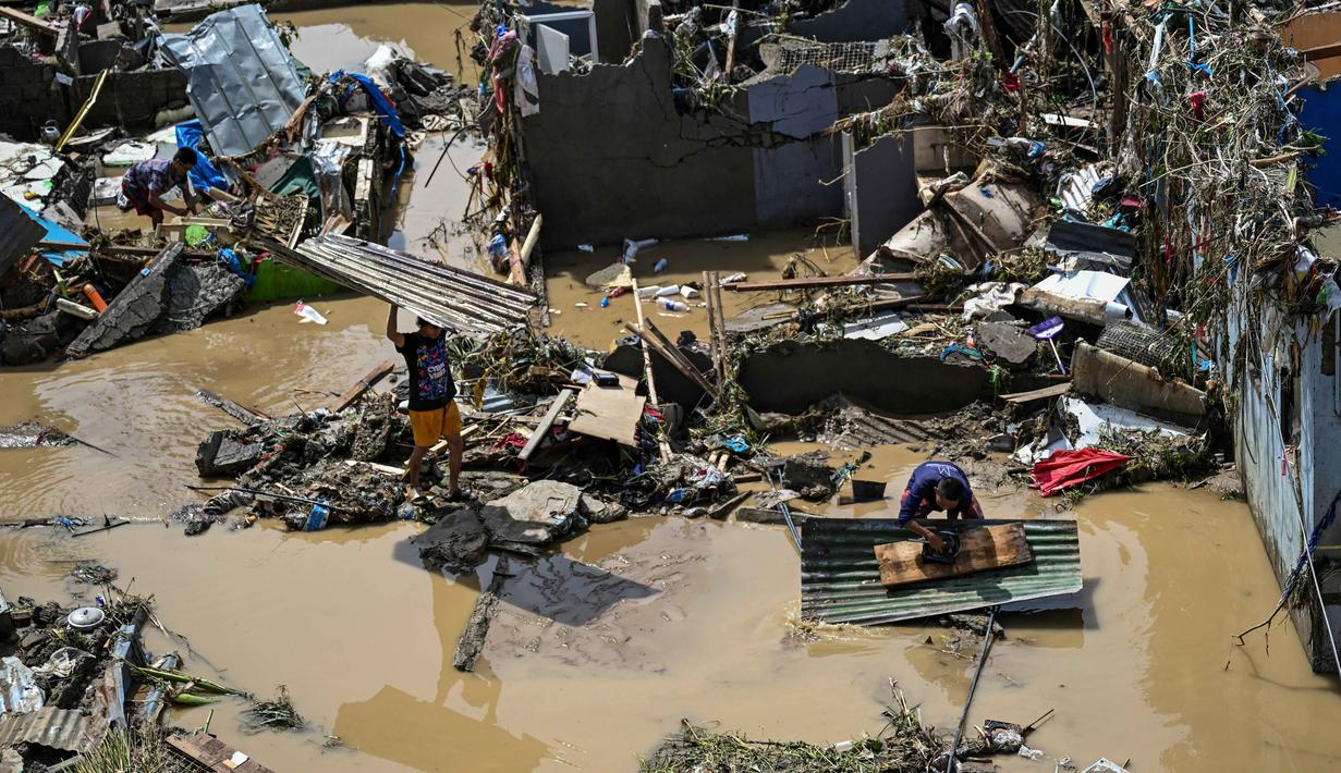Warga membersihkan puing-puing dari rumah-rumah mereka yang rusak akibat terjangan Topan Kalmaegi di Talisay, Provinsi Cebu, Filipina pada Rabu 5 November 2025. Banjir yang dipicu terjangan Topan Kalmaegi di sebagian besar wilayah Filipina pada Selasa (4/11/2025). (Jam STA ROSA/AFP)