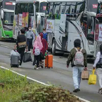 Peserta Mudik Aman Mudik Sehat Kementerian Perhubungan membawa barang bawaan mereka berjalan menuju bus tujuan kampung halamannya di Terminal Jatijajar, Depok, Jawa Barat, Kamis (28/4/2022). Pengguna jasa transportasi bus yang mengikuti program mudik gratis didominasi oleh pemudik yang berasal dari Jawa Tengah dan Jawa Timur dengan syarat telah menerima vaksin booster. (Liputan6.com/Faizal Fanani)