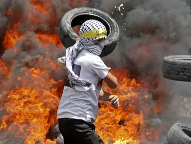 Pengunjuk rasa Palestina membakar ban di tengah bentrokan dengan pasukan keamanan Israel menyusul demonstrasi menentang perampasan tanah oleh Israel di Desa Kfar Qaddum dekat pemukiman Yahudi Kedumim, Tepi Barat, 6 Mei 2022. (JAAFAR ASHTIYEH/AFP)