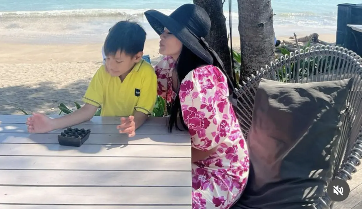 Titi Kamal tampil dengan dress merah lengan puff bermotif bunga mawar, dipadukam topi pantai hitamnya. @titi_kamall