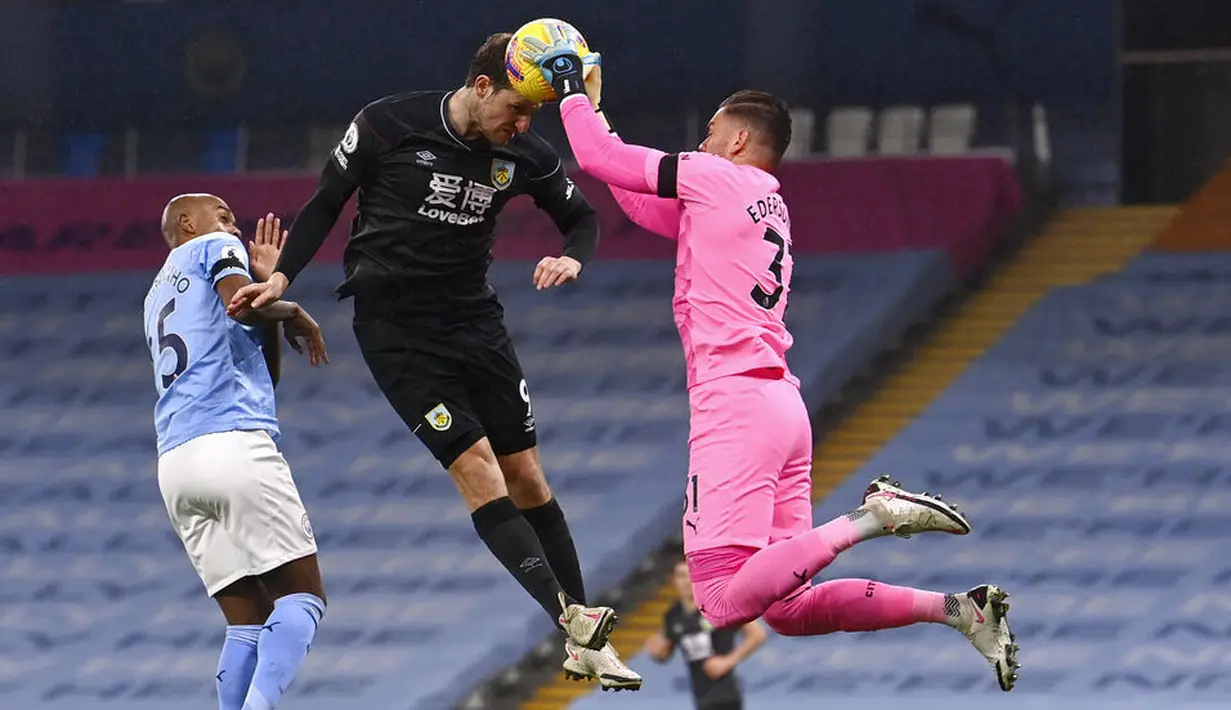 Kiper Manchester City,  Ederson, berebut bola dengan pemain Burnley, Chris Wood, pada laga Liga Inggris di Stadion Etihad, Sabtu (28/11/2020). City menang dengan skor 5-0. (Laurence Griffiths/Pool via AP)