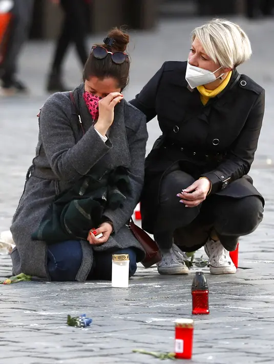 Orang-orang memberi hormat kepada para korban pandemi COVID-19 di Alun-Alun Kota Tua, Praha, Republik Ceko, Senin (29/3/2021). Republik Ceko dan Slovakia jadi antara negara terparah terkena dampak COVID-19, akhirnya mengalami beberapa perbaikan setelah penguncian ketat. (AP Photo/Petr David Josek)