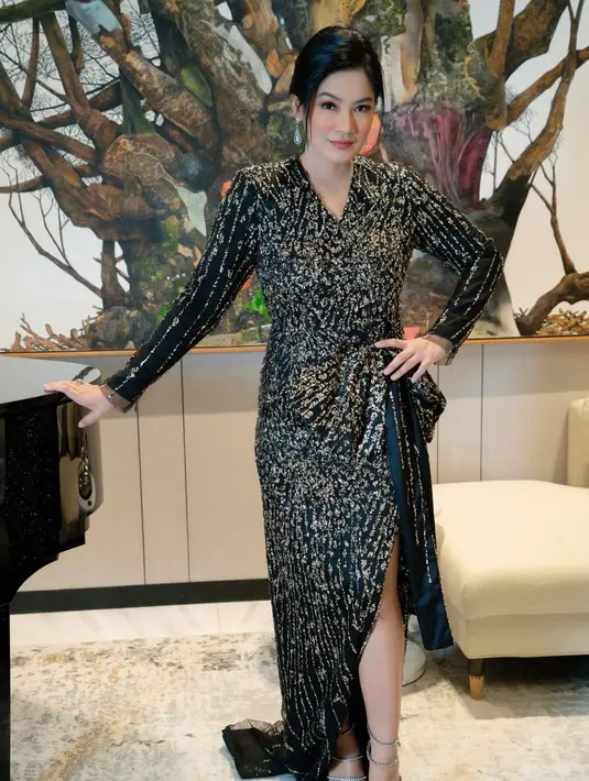 Dress ini memiliki detail high slit yang ujungnya merupakan pita tepat di bagian pinggang. Detail manis lainnya adalah nuansa emas di seluruh gaun hitam yang dikenakan Titi Kamal ini, menambah kesan mewah nan elegan pada keseluruhan penampilannya. Foto: Instagram.