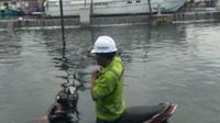 Seorang pekerja berusaha mengeluarkan sepeda motornya yang terendam banjir rob, Senin (23/5/2022). Foto: Liputan6.com/Felek Wahyu&nbsp;
