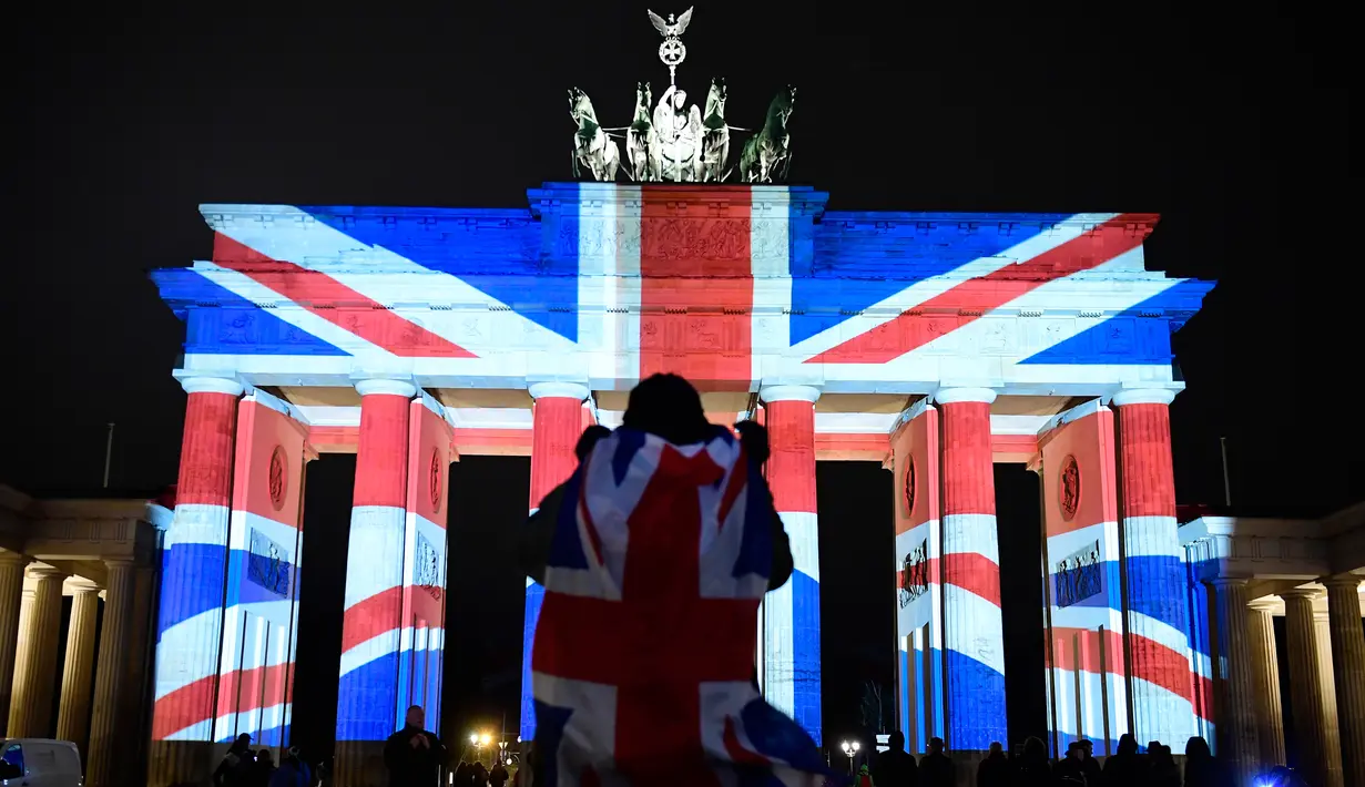 Pengunjung mengamati gerbang bersejarah Brandenburg yang diterangi dengan warna bendera kebangsaan Inggris sebagai bentuk turut berduka cita atas teror London yang menewaskan lima orang, di ibu kota Jerman, Berlin, Kamis (23/3). (Tobias SCHWARZ/AFP)