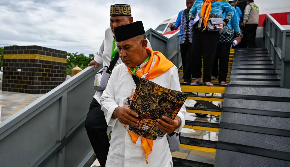 Para calon jemaah haji Indonesia turun dari pesawat Boeing 737 yang sudah tidak digunakan lagi selama sesi pelatihan keselamatan pra-keberangkatan di pusat embarkasi haji Banda Aceh pada Kamis 14 Mei 2026. (CHAIDEER MAHYUDDIN/AFP)